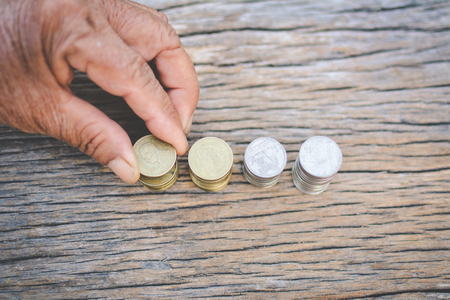 Hand holding coin on old wood background.concept save moneyの写真素材