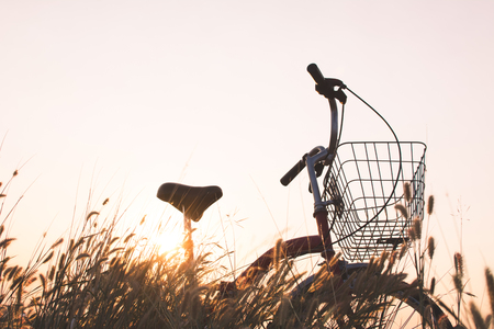 Silhouette of bicycle on grass with the sky sunsetの写真素材