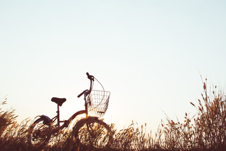 Silhouette of bicycle on grass with the sky sunsetの写真素材