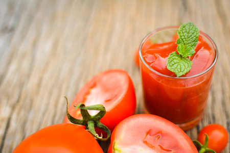 tomato sauce in a glass and fresh tomatoes on old woodの写真素材