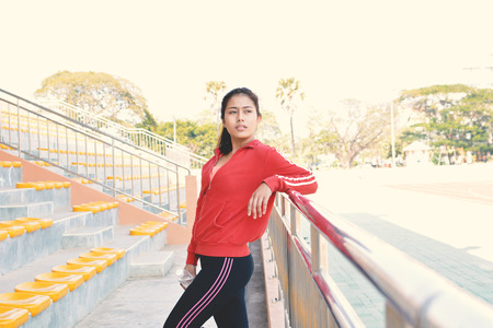 Young women holding water bottle after exercise in stadium