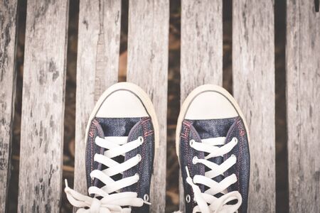 Jeans sneakers on old wooden background and copy space, color of hipster tone and soft focus