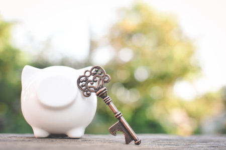 Old key piggy bank on wood a bokeh background with copy space a color of vintage tone selective and soft focus, concept save moneyの写真素材
