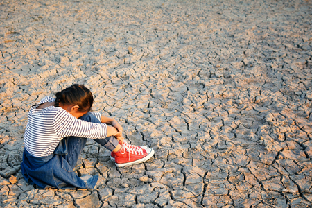 Sad a girl sitting on dry ground .concept hope and droughtの写真素材