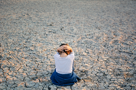 Sad a girl sitting on dry ground .concept hope and droughtの写真素材