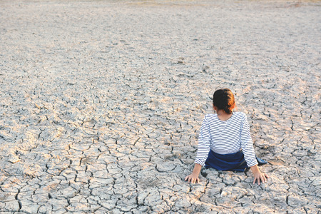 Sad a girl sitting on dry ground .concept hope and droughtの写真素材