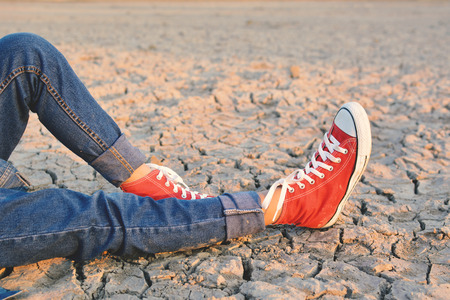 Feet sneaker on crack dry ground, concept droughtの写真素材