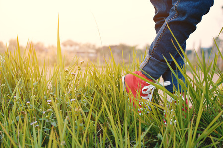 Feet red sneaker a girl in nature and relax time on holiday. selective and soft focus color of vintage toneの写真素材