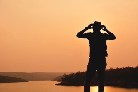 Silhouette of happy Asian hipster man backpack in nature background, Relax time on holiday concept travel , color of vintage tone and soft focusの写真素材