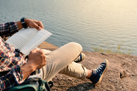 Happy Asian hipster man reading a book in nature background, Relax time on holiday concept travel , color of vintage tone and soft focusの写真素材