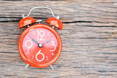 Red alarm clock on old wood background,color of vintage tone selective focus