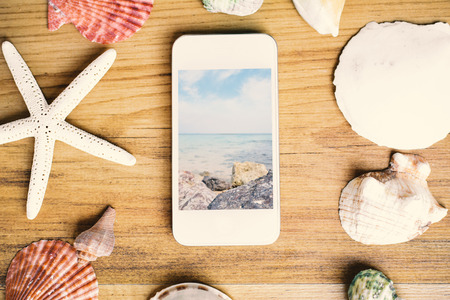 Smartphone and hell on brown wood background, concept summer timeの写真素材