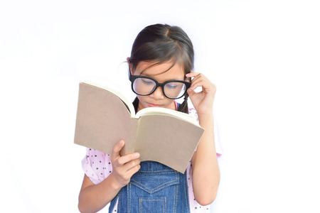 Portrait of little Asian girl reading a book on white backgroundの写真素材