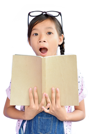 Portrait of little Asian girl holding a book on white backgroundの写真素材