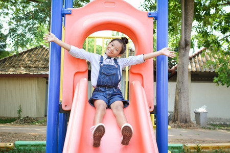 Asian girl playing in playground happy on holiday selective and soft focusの写真素材