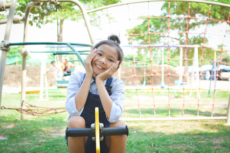 Asian girl playing in playground happy on holiday selective and soft focusの写真素材