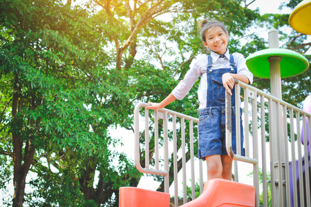 Asian girl playing in playground happy on holiday selective and soft focusの写真素材