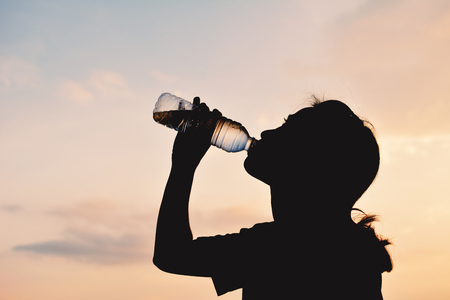 Silhouette women drinking water at sky sunset background ,color style hipster toneの写真素材