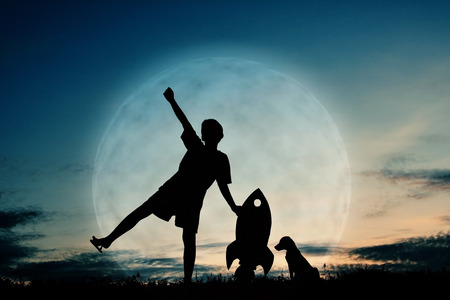 Silhouette boy holding a rocket paper and playing with little dog on the sky with moon background  color of vintage toneの写真素材
