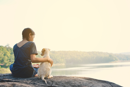 Happy girl playing with little dog in nature background, travel on holiday color of vintage toneの写真素材