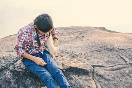 Happy girl playing with little dog in nature background, travel on holiday color of vintage tone and soft focusの写真素材