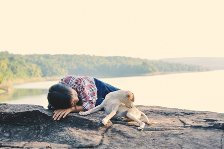 Happy girl playing with little dog in nature background, travel on holiday color of vintage tone and soft focusの写真素材