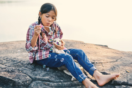 Happy girl playing with little dog in nature background, travel on holiday color of vintage tone and soft focusの写真素材