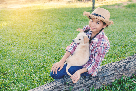 Happy girl playing with little dog in nature background, travel on holiday color of vintage tone and soft focusの写真素材