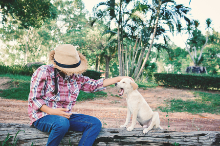 Happy girl playing with little dog in nature background, travel on holiday color of vintage tone and soft focusの写真素材