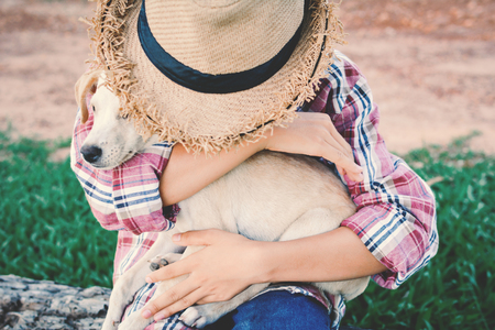 Happy girl playing with little dog in nature background, travel on holiday color of vintage tone and soft focusの写真素材