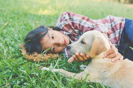 Happy girl playing with little dog in nature background, travel on holiday color of vintage tone and soft focusの写真素材