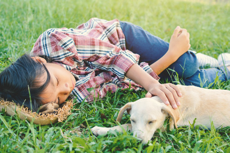 Happy girl playing with little dog in nature background, travel on holiday color of vintage tone and soft focusの写真素材