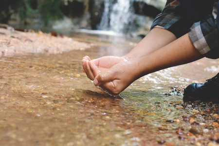 women backpack and drinking water in river creek on forestの写真素材