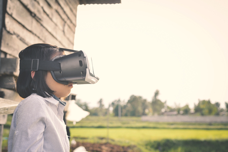 Asian girl playing VR virtual reality glass box outdoor in grass field ,color of vintage style and soft focusの写真素材