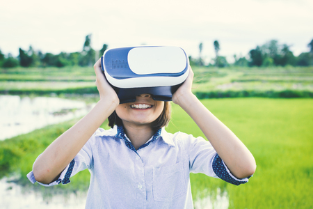 Asian girl playing VR virtual reality glass box outdoor in grass field ,color of vintage style and soft focusの写真素材