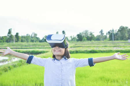 Asian girl playing VR virtual reality glass box outdoor in grass field ,color of vintage style and soft focusの写真素材