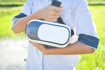 Happy girl holding VR virtual reality glass box on green field,color of vintage style and soft focusの写真素材