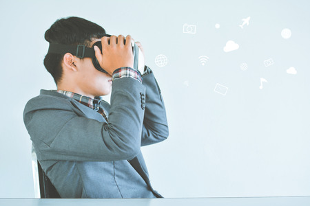 Asian businessman playing VR virtual reality glass box with icon selective and soft focusの写真素材