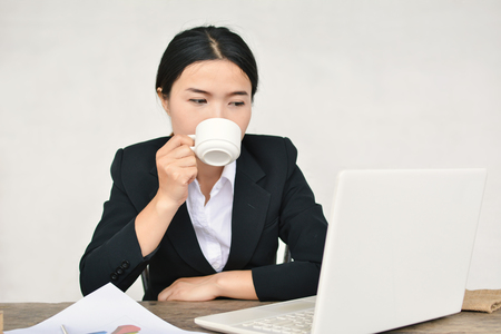 Close up of businesswomen drinking coffee during working in office selective and soft focusの写真素材