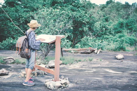 Happy Asian girl reading guide post in forest background , concept backpacker hipster toneの写真素材