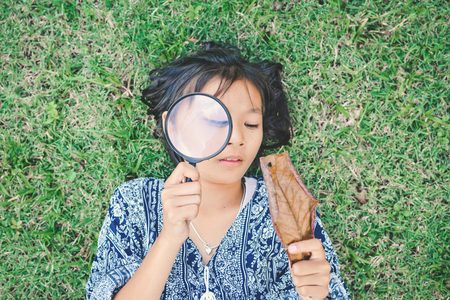 Asian girl hand holding magnifying glass in garden color of hipster tone selective soft focus, concept natural explorerの写真素材