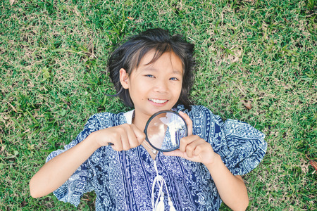 Asian girl hand holding magnifying glass in garden color of hipster tone selective soft focus, concept natural explorerの写真素材