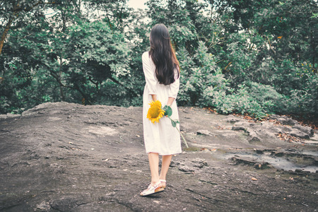 Hipster women hand holding sunflower in forest backgroundの写真素材