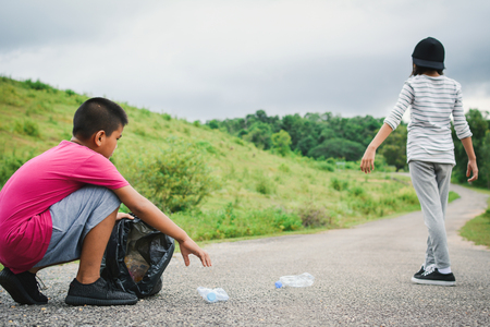 Children picking up empty of bottle plastic into bin bag ,volunteer concept selective and soft focusの写真素材