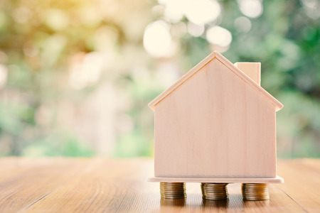 Coins and wood house on table tree bokeh background concept save money for home ,selective and soft focus vintage toneの写真素材