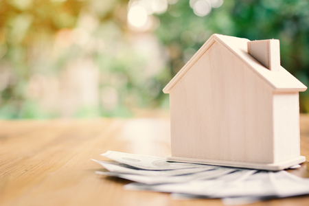 Wood house with dollar money on table tree bokeh background concept save money for home ,selective and soft focus vintage toneの写真素材