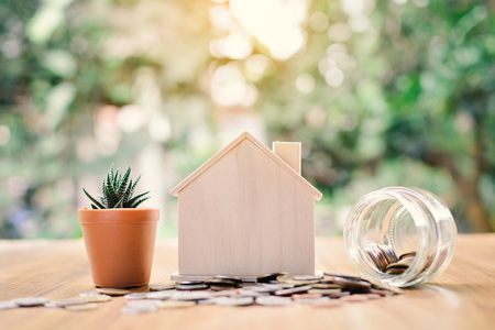 Coins and wood house with cactus on table tree bokeh background concept save money for home ,selective and soft focus vintage toneの写真素材