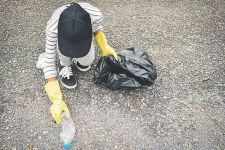 Girl hand in yellow gloves picking up empty of bottle plastic into bin bag ,volunteer conceptの写真素材
