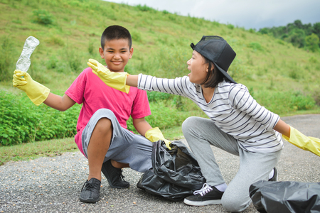 Children hands in yellow gloves picking up empty of bottle plastic into bin bag ,volunteer concept selective and soft focusの写真素材