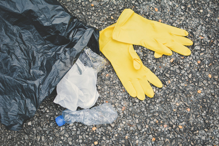 Close up yellow gloves and garbage bin bag on road backgroundの写真素材